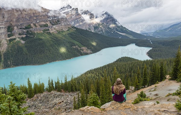 Young woman sitting on a stone looking into nature