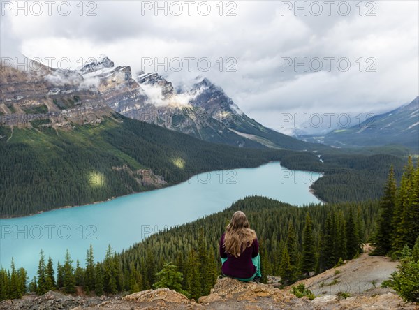 Young woman sitting on a stone looking into nature