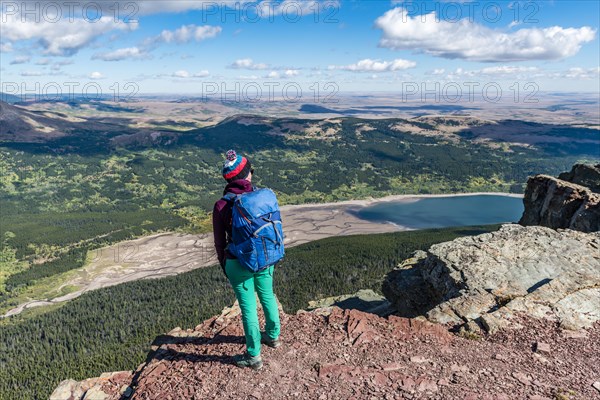Young hiker standing at the view of mountain lake Lower Two Medicine Lake with mountain landscape