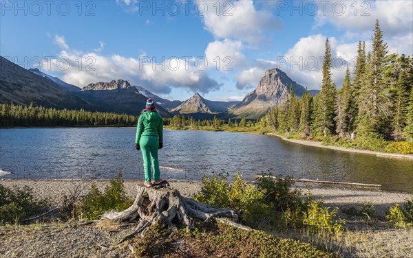 Young woman looking at mountain lake Two Medicine Lake in mountain landscape