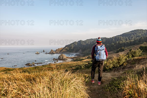 Young woman on a hiking trail along the rugged coast with many rocks