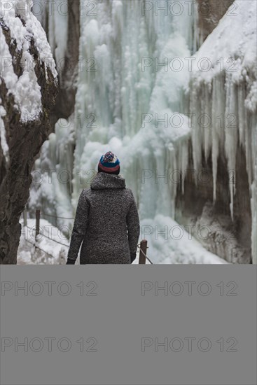 Young woman in the icy Partnachklamm with icicles and snow in winter