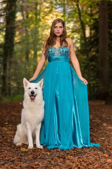 Woman with long turquoise-blue evening dress and white shepherd dog