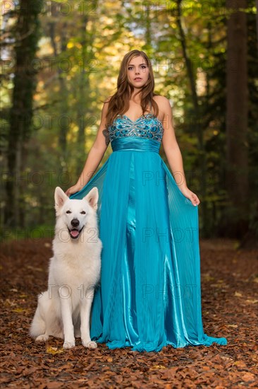 Woman with long turquoise-blue evening dress and white shepherd dog