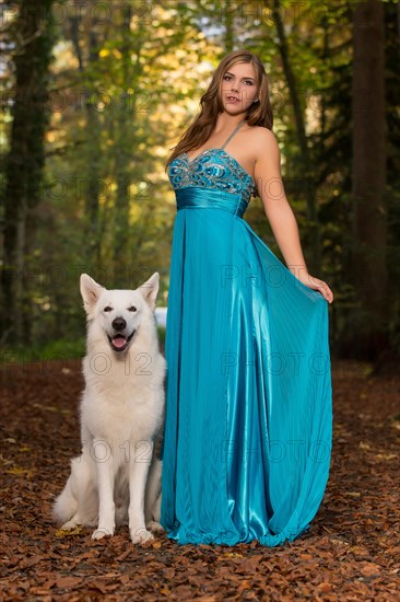 Woman with long turquoise-blue evening dress and white shepherd dog
