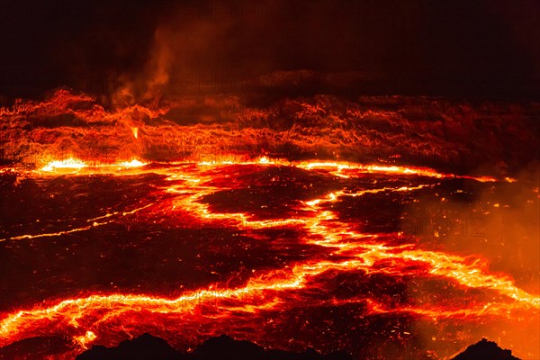 Glowing lava lake with eruptions at night