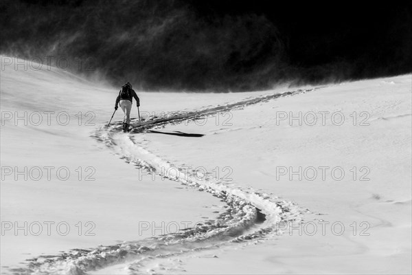 Ski mountaineer in winter landscape against a dark background