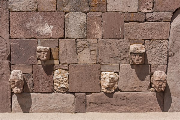 Stone heads in wall of Kalasasaya temple (place of standing stones) with monoliths from pre-Inca period