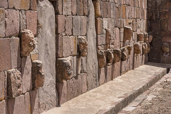 Stone heads in wall of Kalasasaya temple (place of standing stones) with monoliths from pre-Inca period
