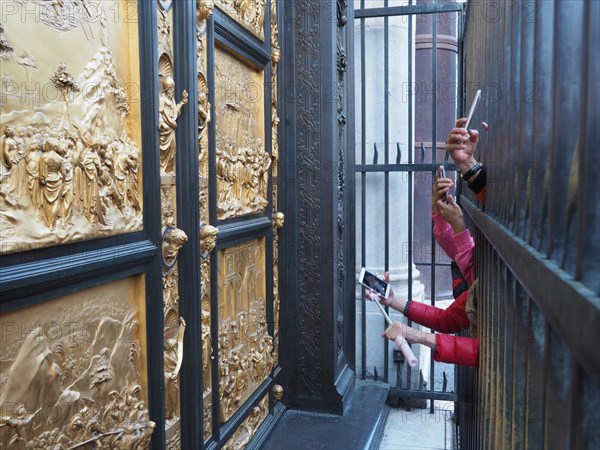 Tourists photograph with smartphone the paradise door in Florence