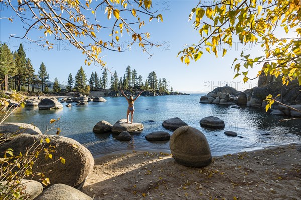 Young woman in bikini standing on a round stone in the water