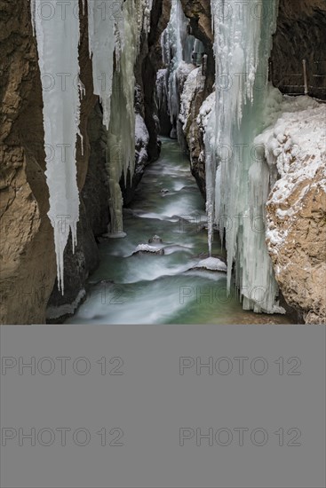 Path to Partnach wild river in the Partnach gorge with long icicles and snow in winter
