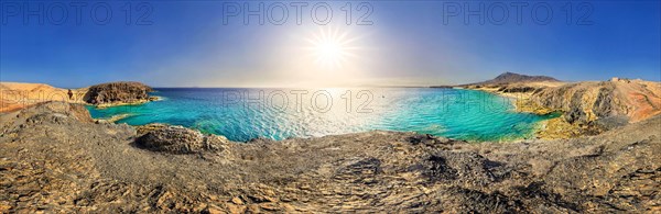 Panorama with sun on rocky coast with turquoise waters of Playa del Papagayo