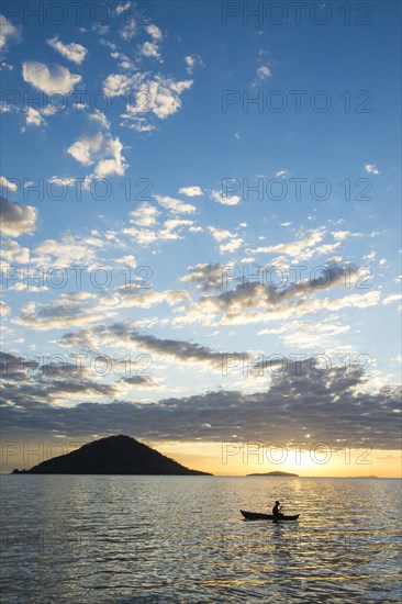 Man in a little fishing boat at sunset