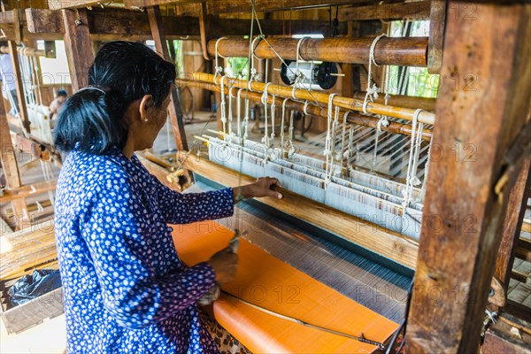 Native woman weaves on a loom