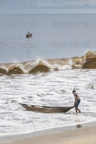 Fisherman with a dugout canoe on the beach