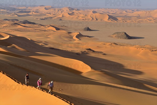 Group of people hiking in the sanddunes of Egedi In Djerane