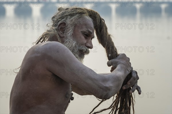 Sadhu drying his dreadlocks on Ganges riverbank