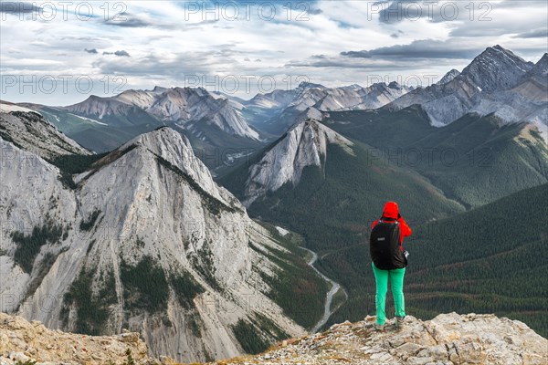 Female hiker views from summit over mountain landscape