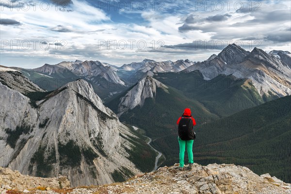 Female hiker views from summit over mountain landscape