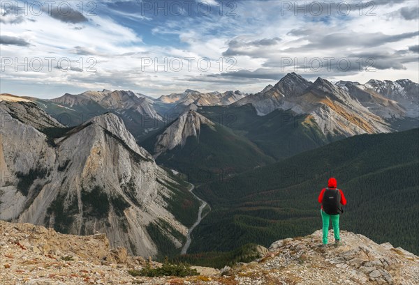 Female hiker looks from summit over mountain landscape