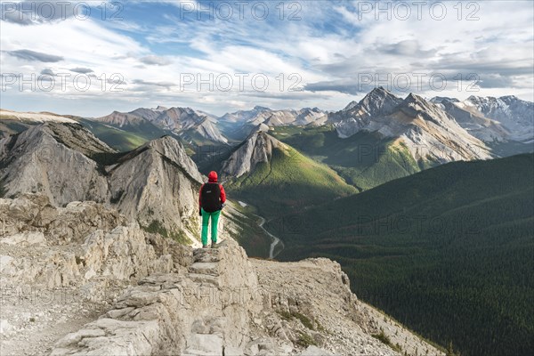 Female hiker views from summit over mountain landscape