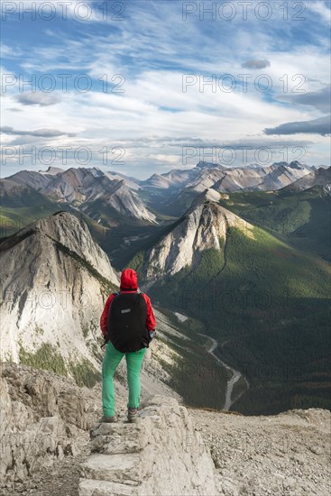 Female hiker views from summit over mountain landscape