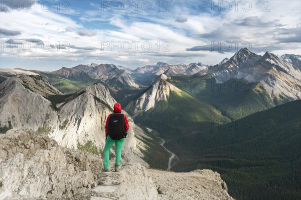 Female hiker views from summit over mountain landscape