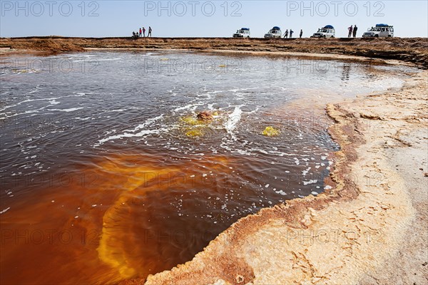 Tourists near salt lake with geothermal springs and petrified salt crystals