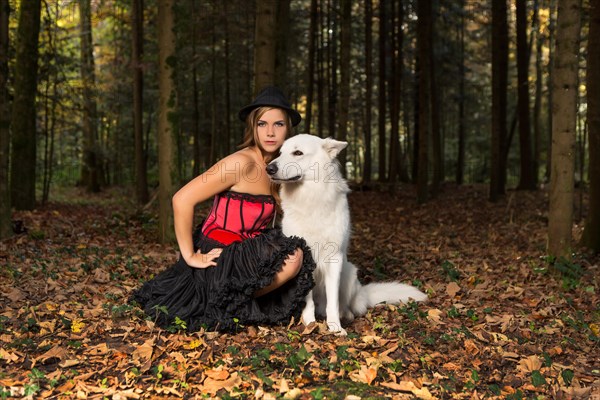 Blonde woman with white shepherd dog in the forest