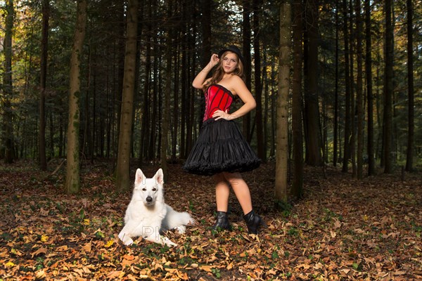 Blonde woman with white shepherd dog in the forest