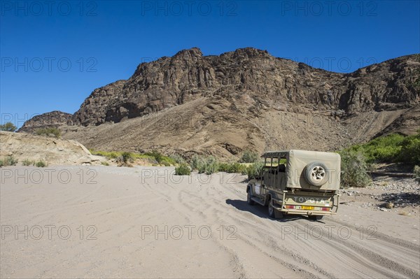 Tourist jeep driving through the deep sand searching for safari