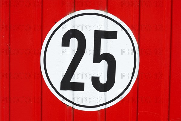 Road sign speed limit 25 Km/h on red wood wall