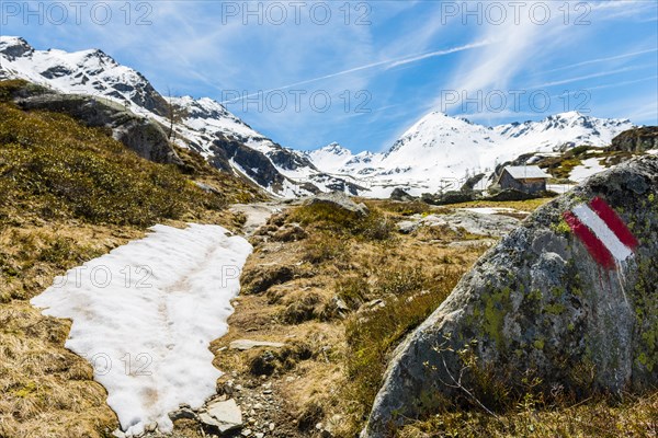 Red and white sign painted on rock marking hiking trail