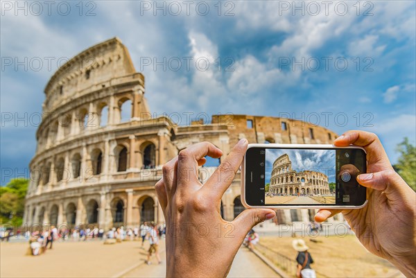 Hands of tourist photographing the Colosseum with smartphone