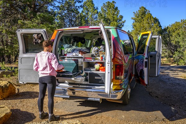 Young woman cooking at the gas stove of a camping van