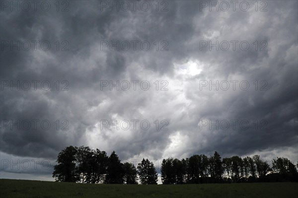 Storm clouds over field and row of trees in Beuerberg