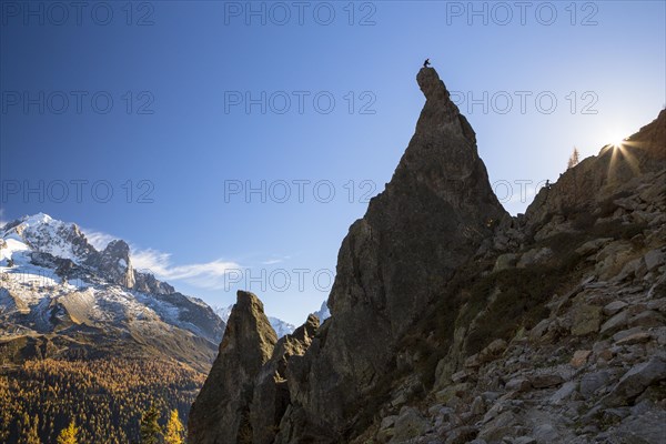 Climber standing on rocky pinnacle overlooking the mountains of Chamonix