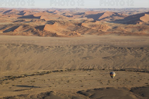 Hot-air balloon above an arid plain and the dry riverbed of the Tsauchab river at the edge of the Namib Desert