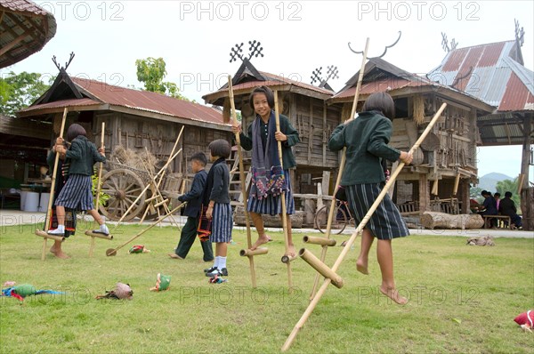 Tai Dam children walking on bamboo stilts