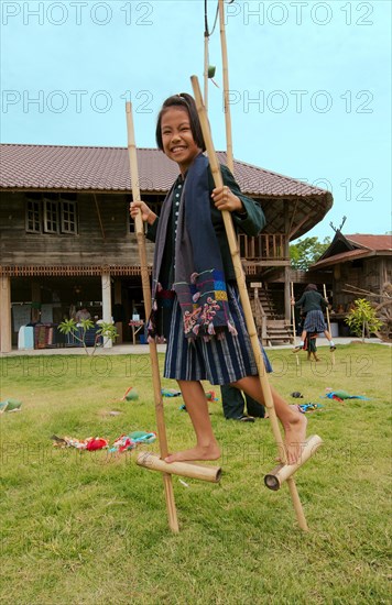 Tai Dam children walking on bamboo stilts