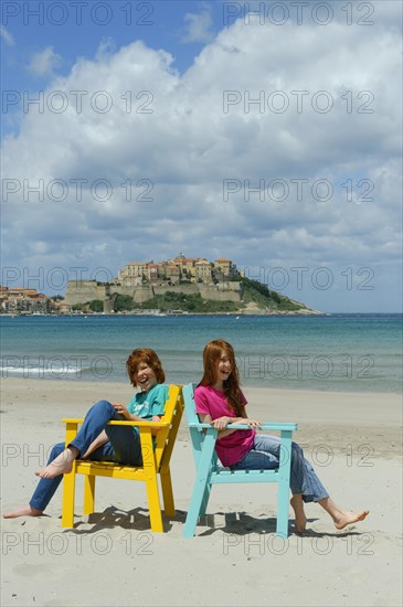 Children sitting in colorful beach chairs on the beach of Calvi