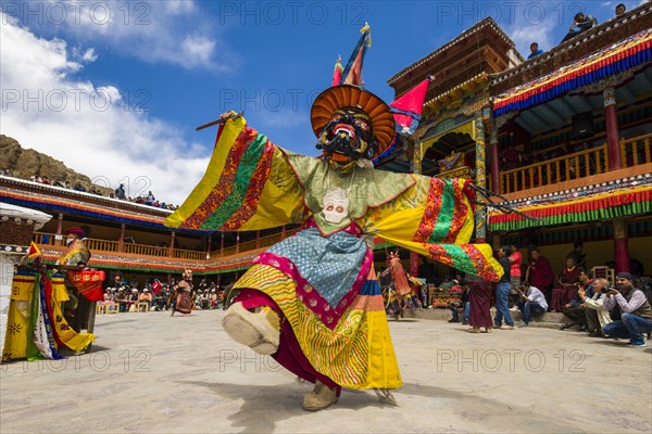 Monks with big wooden masks and colorful costumes are performing ritual dances at Hemis Festival in the courtyard of the monastery