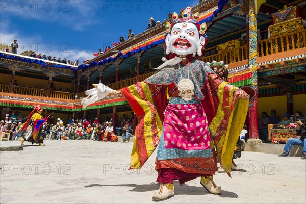 Monks with big wooden masks and colorful costumes are performing ritual dances at Hemis Festival in the courtyard of the monastery