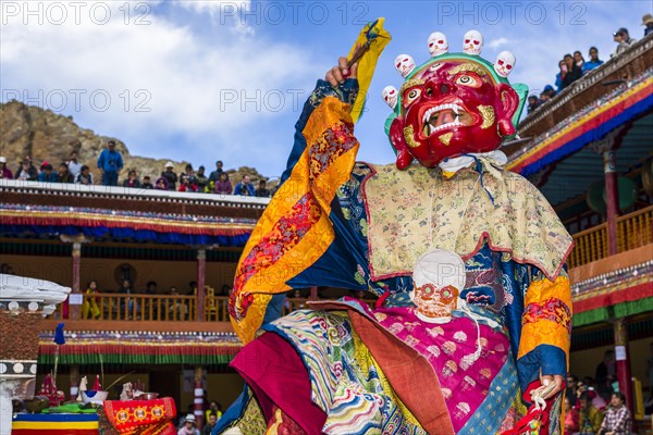 Monks with big wooden masks and colorful costumes are performing ritual dances at Hemis Festival in the courtyard of the monastery