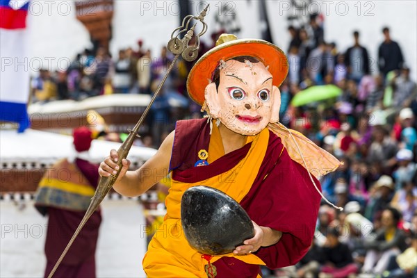 Monks with big wooden masks and colorful costumes are performing ritual dances at Hemis Festival in the courtyard of the monastery