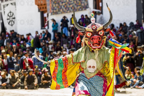 Monks with big wooden masks and colorful costumes are performing ritual dances at Hemis Festival in the courtyard of the monastery