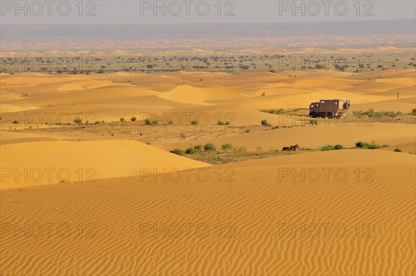 Truck with camping space passing through sand dunes