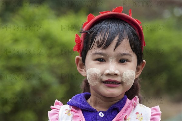 Local girl with a red cap and Thanaka paste on her face