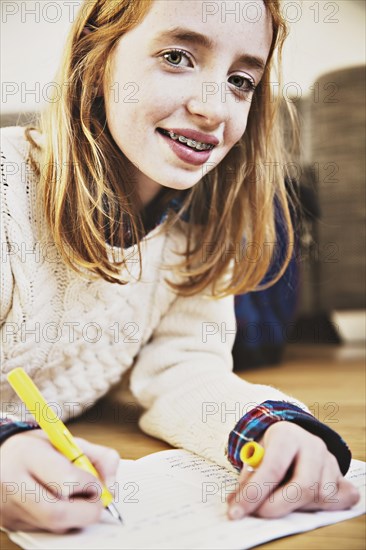 Girl doing her homework on the floor at home
